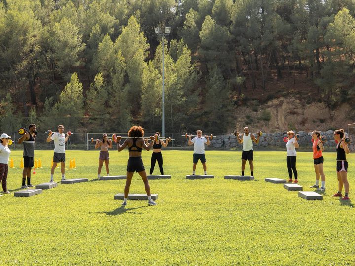 Adhérents de l'association La Meute de Montferrier en cercle, barre sur les épaules, lors d'une séance de renforcement musculaire en plein air encadrée par Aurélie Kamga, stade Christian Bougette, 34980 Montferrier-sur-Lez