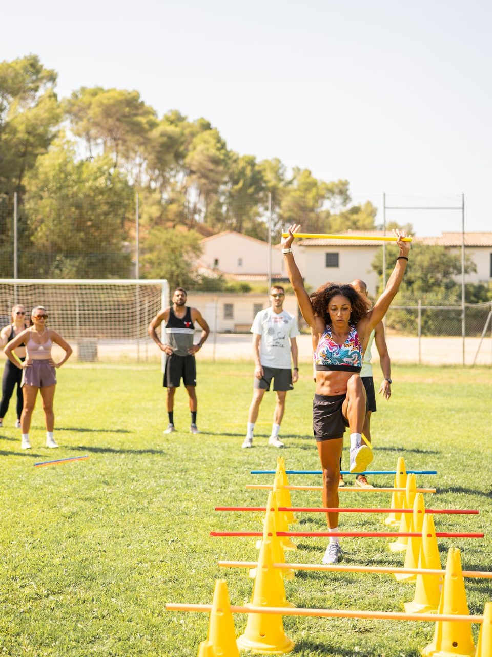 Aurélie Kamga, coach sportif à Montferrier-sur-Lez, démontre un exercice de coordination sur haies devant un groupe, au stade Christian Bougette